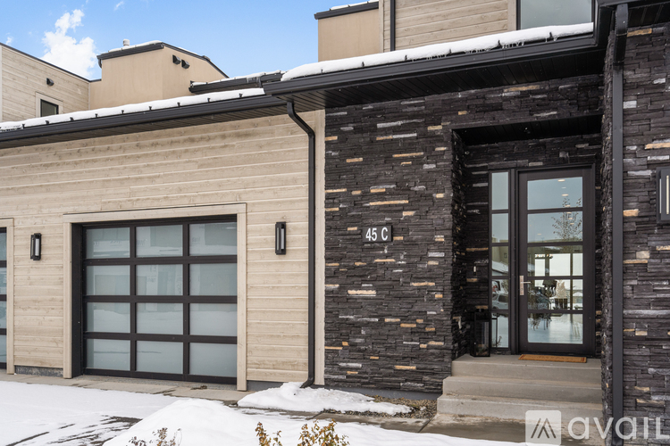 A modern house with a stone and wood exterior and a glass door.