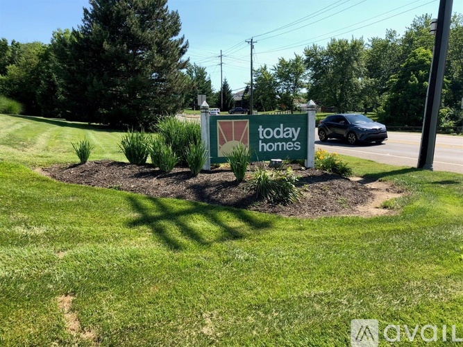A sign for "today homes" is in the foreground with a car and trees in the background.