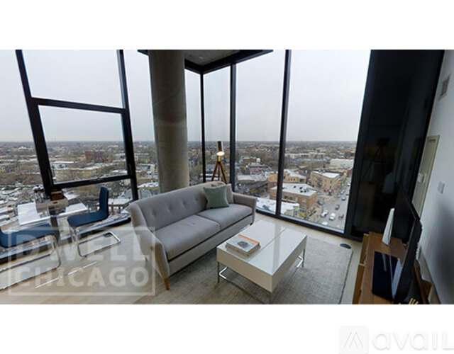 A living room with a couch and a table in front of a large window overlooking a city.