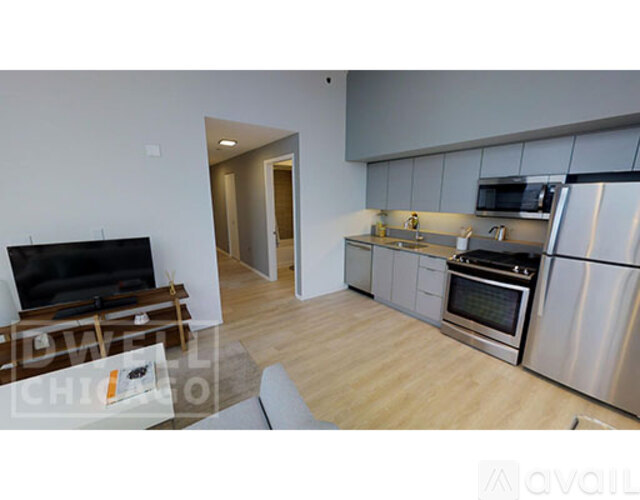 A modern kitchen with stainless steel appliances and a flat screen TV.