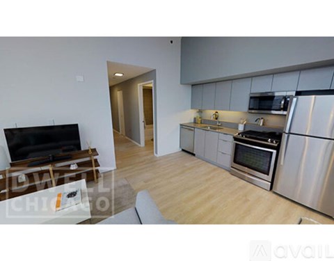 A modern kitchen with stainless steel appliances and a flat screen TV.