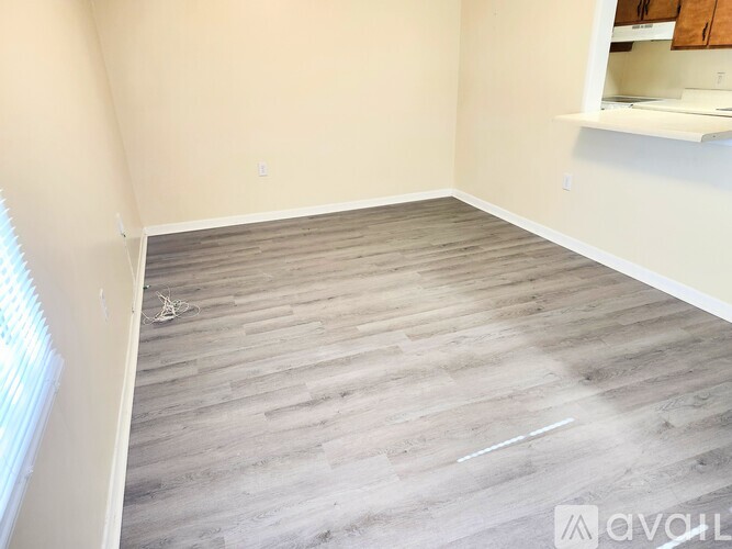 A room with wooden flooring and a window on the left side.