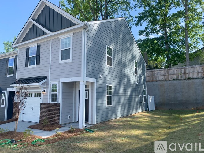 A house with a grey exterior and a black roof is available for purchase.