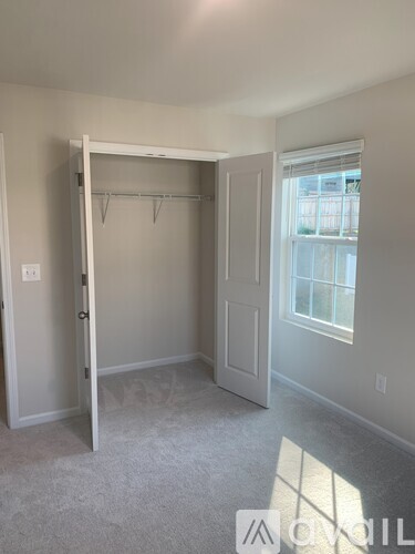A bedroom with a white door and a window.