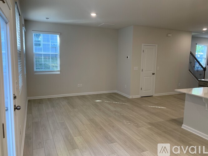 A spacious room with light wood flooring and white walls.