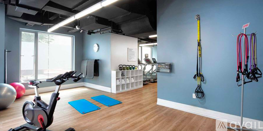 A gym with a variety of equipment including a stationary bike, resistance bands and a yoga ball.