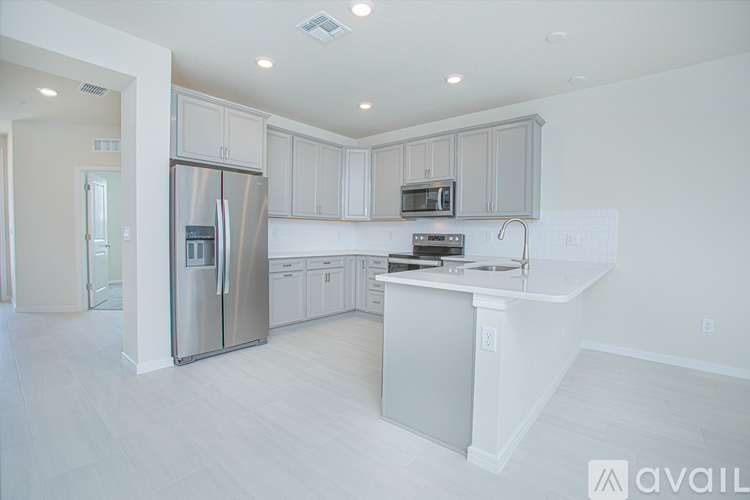 A modern kitchen with white cabinets and a stainless steel refrigerator.