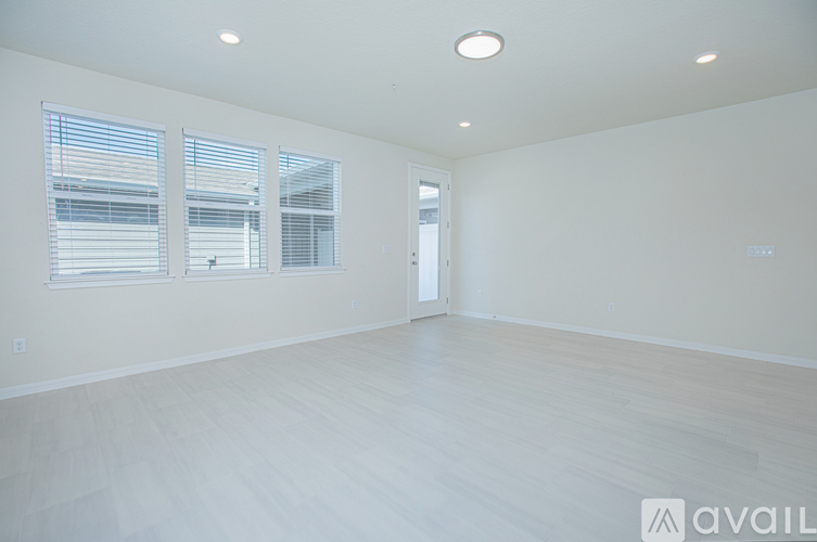 A spacious room with a door, windows, and a wooden floor.