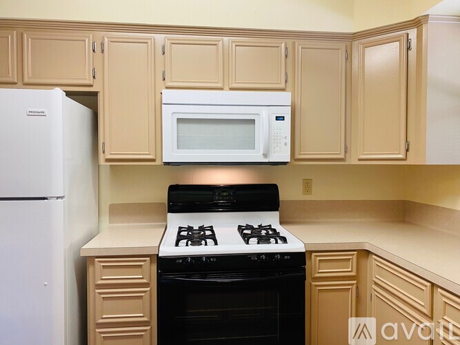 A kitchen with a white refrigerator, a black stove, and a white microwave above the stove.