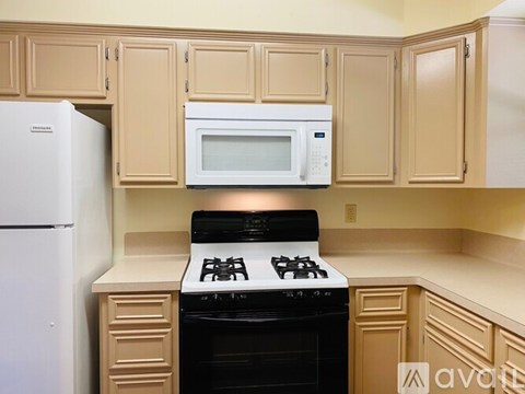 A kitchen with a white refrigerator, a black stove, and a white microwave above the stove.