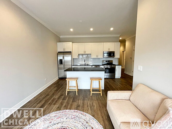 A kitchen with white cabinets and a countertop with a bar stool in front of it.