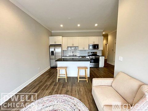 A kitchen with white cabinets and a countertop with a bar stool in front of it.