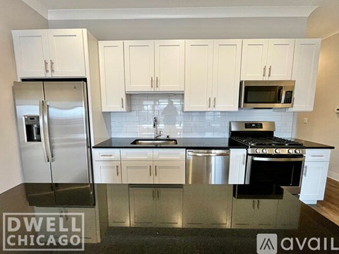 A kitchen with white cabinets and a black countertop.