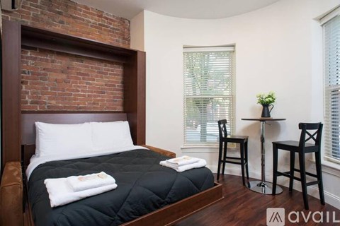 A bedroom with a brick wall and a bed with white pillows.