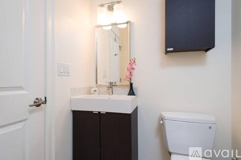 A bathroom with a toilet, sink, mirror, and a door.