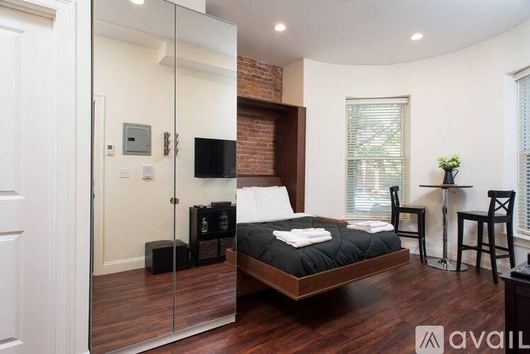 A bedroom with a large bed and a glass walled shower.