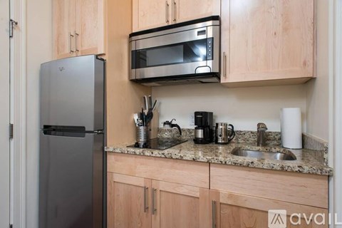 A kitchen with wooden cabinets and a black fridge.