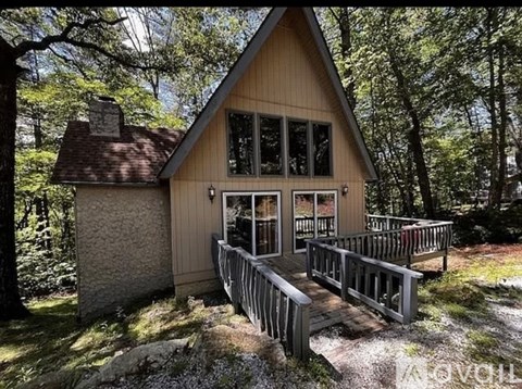 A small wooden cabin with a deck in the woods.