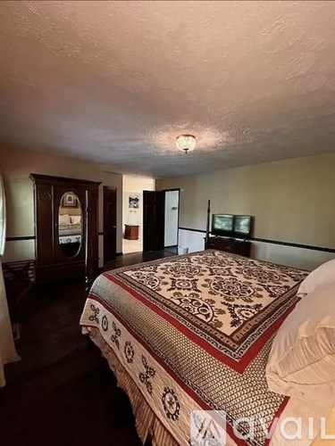 A bedroom with a large bed and a dresser.