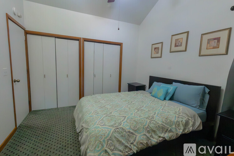 A bedroom with a bed, two pillows, a nightstand, and a wardrobe.