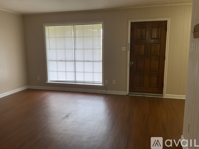 A room with a wooden floor and a window with blinds.