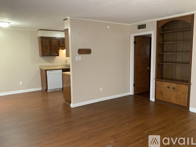 A room with wooden floors and a white wall with a brown door.