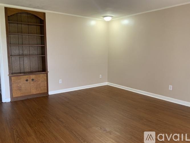 A room with wooden flooring and a cabinet with a glass door.