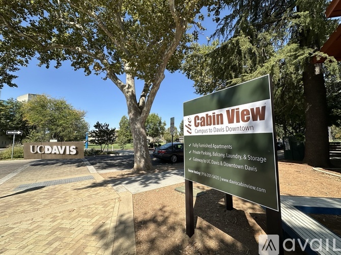 A sign for Cabin View Apartments is displayed in front of a tree.