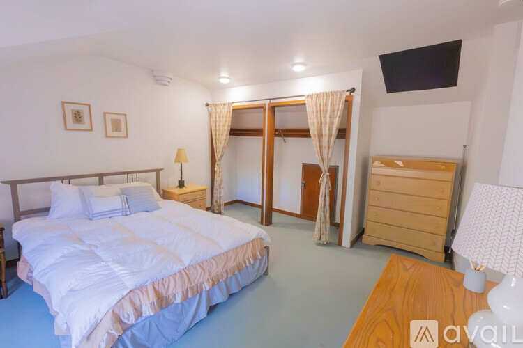 A bedroom with a large bed and a wooden dresser.