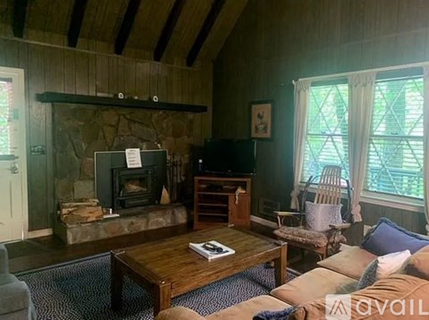 A living room with a stone fireplace and a wooden coffee table.