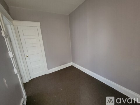 A room with a white door and a wooden floor.