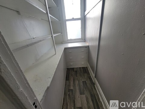 A small room with a window and a wooden floor.