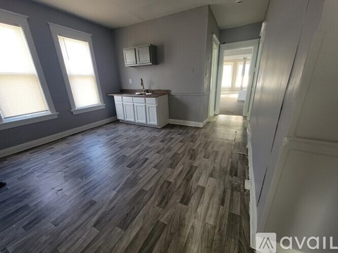 A room with wooden flooring and a cabinet under a window.