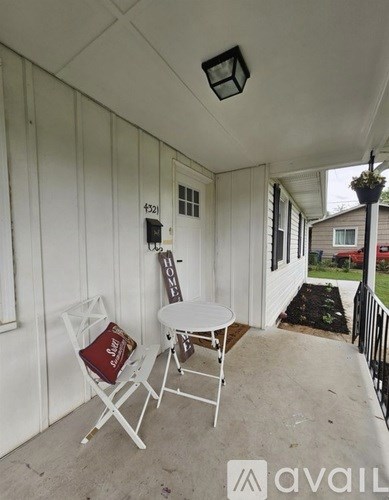 A small white table and two chairs are on a porch.