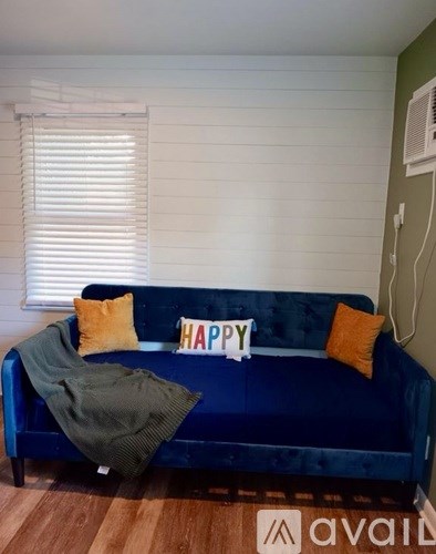 A blue couch with a pillow and a sign that says "HAPPY" on it.