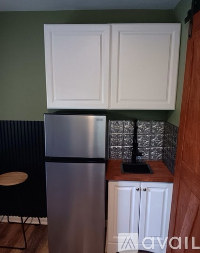 A kitchen with a stainless steel refrigerator and white cabinets.