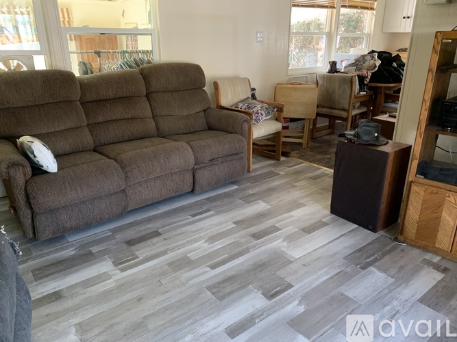 A living room with a brown couch and wooden flooring.
