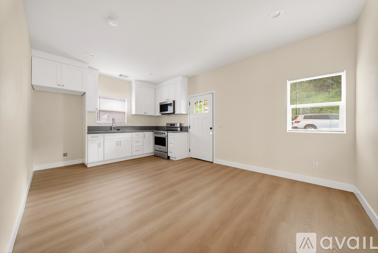 A spacious kitchen with white cabinets and a window overlooking a parking lot.