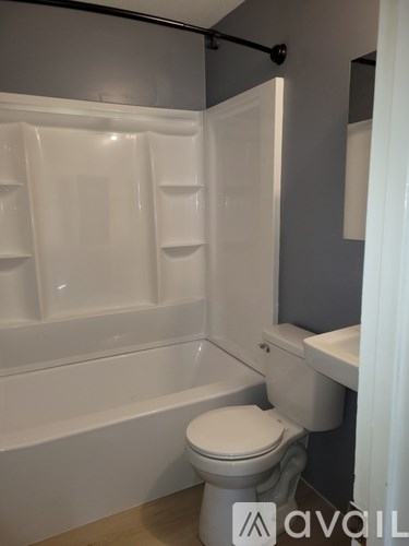 A white toilet sits in a bathroom with a white bathtub and a white shower curtain.