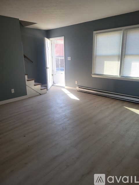 A room with wooden flooring and a staircase leading to a door.