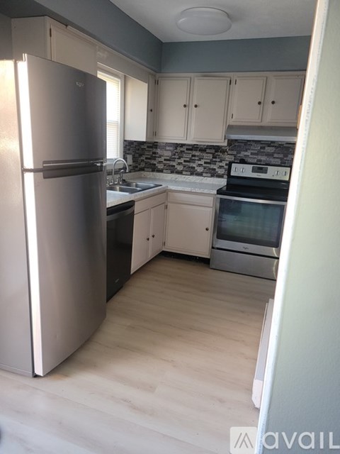A kitchen with a refrigerator, sink, and oven.