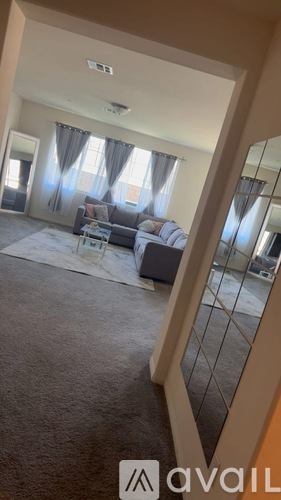 A living room with a grey carpet and a grey sofa.