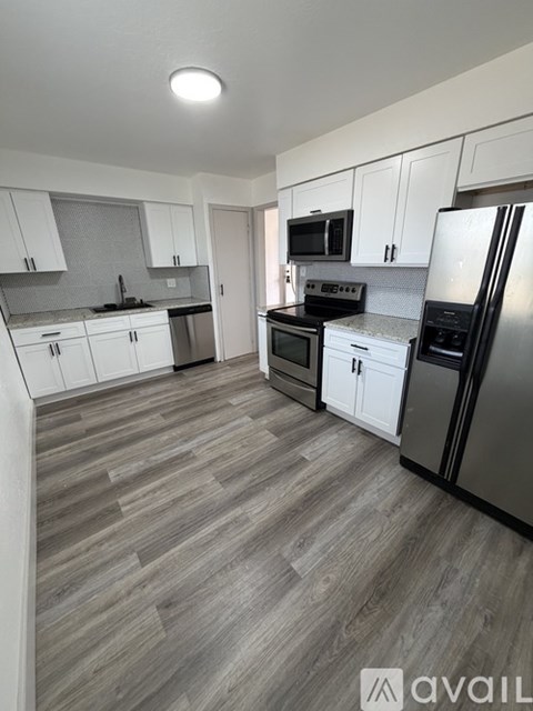A kitchen with white cabinets and a grey floor.