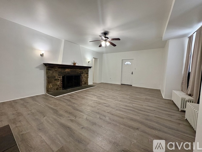 A spacious room with a fireplace and a ceiling fan.
