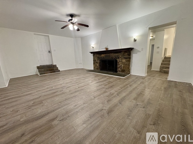 A living room with a fireplace and a ceiling fan.