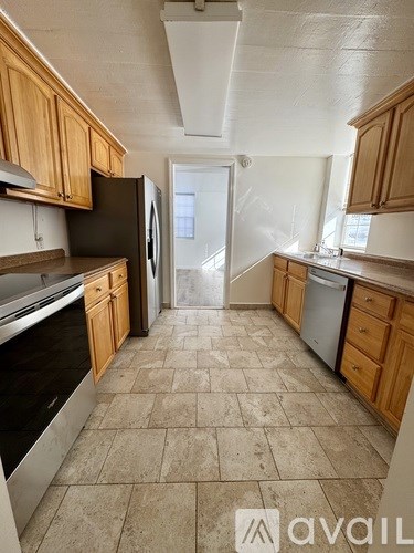 A kitchen with wooden cabinets and tile flooring.