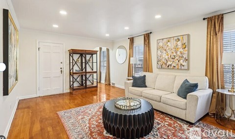 A living room with a white couch and a large painting on the wall.