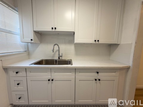 A kitchen with white cabinets and a stainless steel sink.
