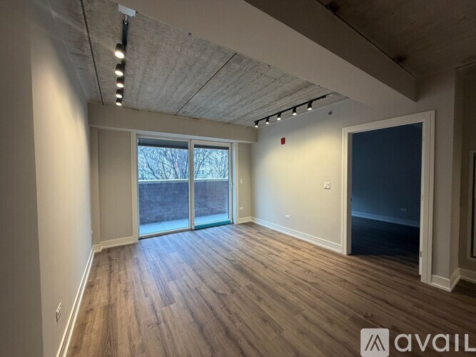 A spacious room with wooden flooring and a large window with a view of a building.