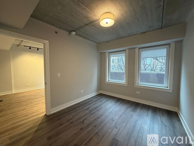 A room with wooden floors and a window with a view of trees.